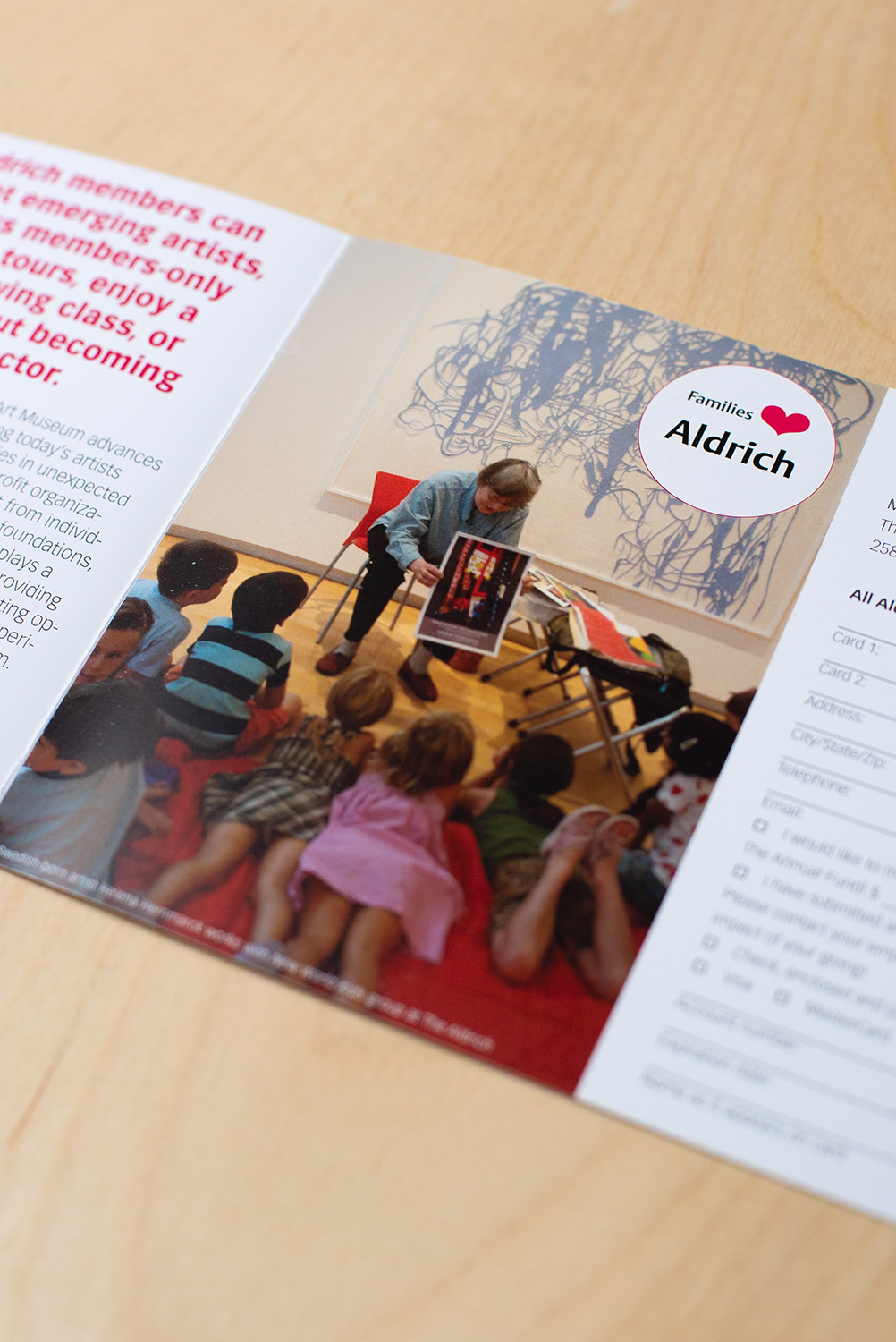 interior of membership brochure for The Aldrich Contemporary Art Museum featuring an image of an artist explaining her work to a group of curious young children