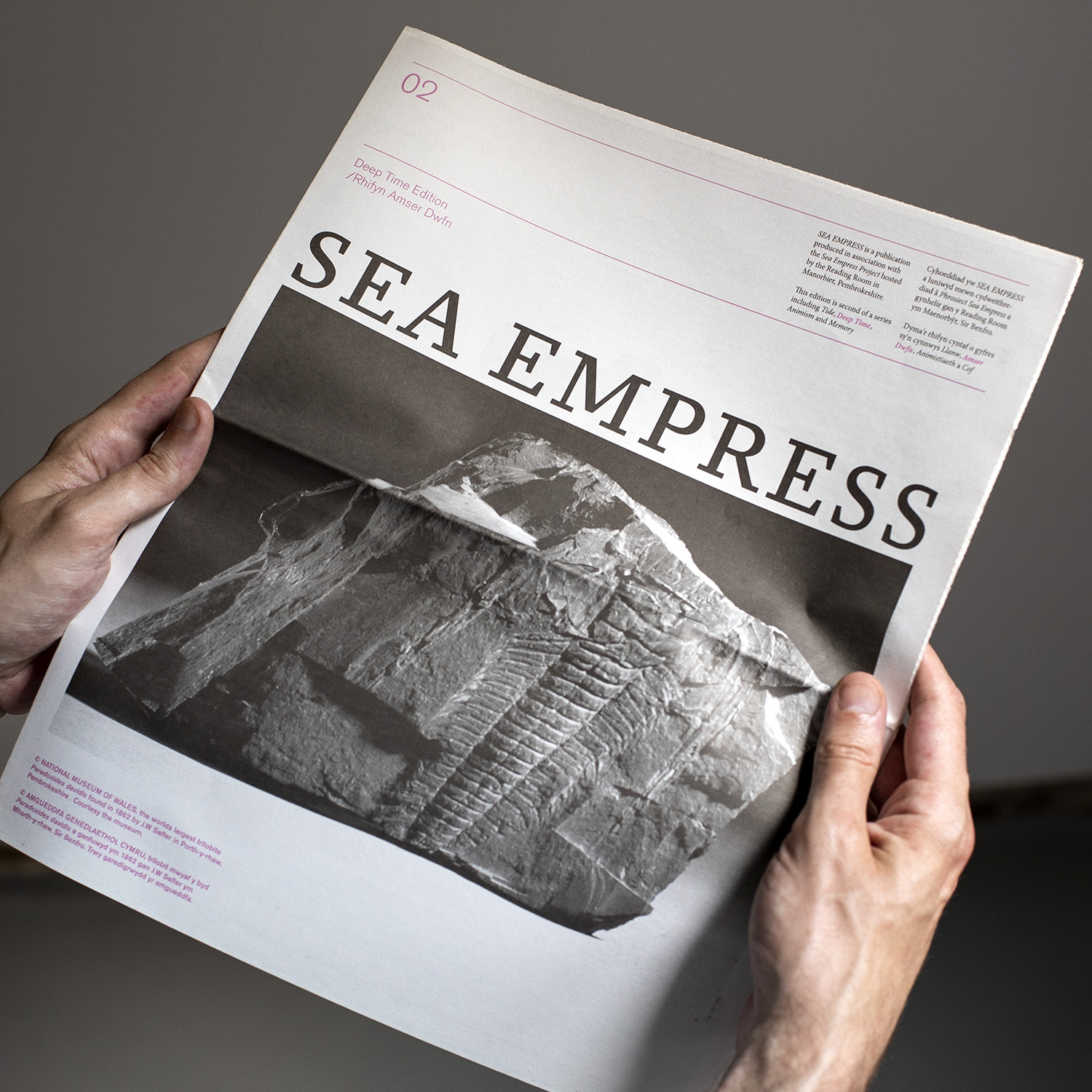 photo of hands holding issue 2 of publication Seaempress: Deep time featuring a cover image of a fossil